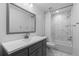 Modern bathroom showcasing a vanity with white countertop, large mirror, and tiled shower with tub at 17960 Weymouth Ave, Parker, CO 80134
