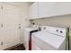 A well-lit laundry room features a washer, dryer, white cabinets, and access to the outside at 24704 E Chenango Dr, Aurora, CO 80016