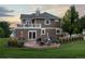 Two-story home showcasing a stone patio with a fire pit, balcony, and a lush green lawn at 5604 Singletree Ln, Parker, CO 80134