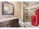 Bathroom with stone countertops, dark cabinets, and glass-enclosed shower stall at 5604 Singletree Ln, Parker, CO 80134