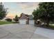 Attached three-car garage with a wide driveway and mature trees set against a colorful evening sky at 5604 Singletree Ln, Parker, CO 80134