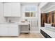Bright laundry room with utility sink, white cabinets, and wood-paneled storage nook at 5604 Singletree Ln, Parker, CO 80134