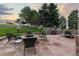 Stone patio with a fire pit, chairs, umbrella, grill, and surrounding mature trees perfect for outdoor entertaining at 5604 Singletree Ln, Parker, CO 80134