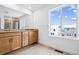 Elegant bathroom featuring double sinks, large mirror, and tiled floor with a scenic window view at 16634 W 93Rd Way, Arvada, CO 80007