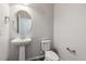 A half bath featuring a pedestal sink, a round mirror, and modern fixtures at 457 Interlocken Blvd # 101, Broomfield, CO 80021