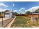 Large backyard with a chain link fence, lush lawn, and a detached garage in the background at 745 S Utica St, Denver, CO 80219