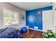 Stylish bedroom featuring a vibrant blue accent wall, hardwood floors, and a bright window at 745 S Utica St, Denver, CO 80219