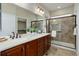 Elegant bathroom with a double sink vanity, a glass shower, and a walk-in closet at 8255 E 150Th Pl, Thornton, CO 80602