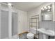 Cozy bathroom featuring a glass enclosed shower, pedestal sink, and open shelving for storage at 10116 Quivas St, Thornton, CO 80260