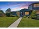 Charming blue home with a well-maintained lawn and landscaping, enhanced by a picturesque sunset sky at 10116 Quivas St, Thornton, CO 80260