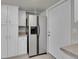 Additional kitchen area featuring white cabinets, a refrigerator and a side entry door at 10116 Quivas St, Thornton, CO 80260