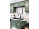 A well-lit kitchen area features green cabinets, white subway tile, and sleek black hardware at 2610 Poplar St, Denver, CO 80207