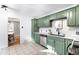 A kitchen featuring updated tiling, stainless steel appliances, quartz countertop, and stylish green cabinetry at 2610 Poplar St, Denver, CO 80207