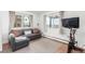 Bright living room featuring a gray sectional sofa, large windows, and an exercise bike at 5761 W 50Th Ave, Denver, CO 80212