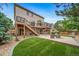Expansive backyard featuring a large deck, lush lawn, mature trees, and patio seating at 9928 Sylvestor Rd, Highlands Ranch, CO 80129
