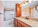 Bright bathroom with granite countertop, wood cabinets, and tiled shower at 9928 Sylvestor Rd, Highlands Ranch, CO 80129