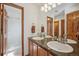 Bathroom with a double sink vanity, granite countertop, wood cabinets, and a door to a shower at 8 Mountain High Ct, Littleton, CO 80127