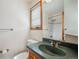 Well-lit bathroom featuring a green countertop sink, toilet, and shower-tub combination at 8 Mountain High Ct, Littleton, CO 80127