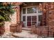 Inviting brick porch with rocking chairs and a decorative glass door, offering a cozy entryway at 8 Mountain High Ct, Littleton, CO 80127