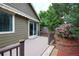Inviting back deck area with awning, railing, and steps leading to a patio space filled with lush landscaping at 13424 W 64Th Pl, Arvada, CO 80004