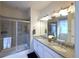Bathroom with double vanity, granite counters, a glass enclosed shower and neutral tile at 13424 W 64Th Pl, Arvada, CO 80004