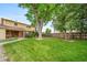 Large backyard features mature trees, lush green lawn, and a wooden fence at 2276 S Dover Way, Lakewood, CO 80227