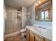 Bathroom featuring walk-in shower with glass doors, wood vanity, and shelving for storage at 2276 S Dover Way, Lakewood, CO 80227