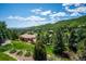 Scenic aerial view of a neighborhood nestled in the foothills, with lush green trees surrounding well-maintained homes at 16442 Rocky Point Ln, Morrison, CO 80465