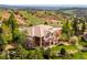 Beautiful exterior elevation of a luxury home featuring stone accents, tile roof, and a deck overlooking a mountain view at 16442 Rocky Point Ln, Morrison, CO 80465