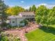 Back exterior view of home featuring the large deck and well manicured landscaping with beautiful natural light at 1579 W Costilla Pl, Littleton, CO 80120