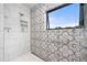 Shower showcasing decorative tile with an inset shelf and a sleek glass enclosure at 1579 W Costilla Pl, Littleton, CO 80120