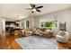 Bright open-concept living room with cozy sectional sofa, ceiling fan, and hardwood floors adjacent to kitchen at 3027 Walnut Grove St, Erie, CO 80516