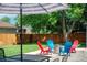 Backyard patio area with colorful Adirondack chairs around a fire pit and an umbrella-shaded dining table at 1650 S Holly St, Denver, CO 80222