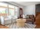 Sunlit living room features a leather couch, two white chairs, and a patterned rug on hardwood floors at 1650 S Holly St, Denver, CO 80222