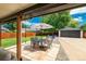 Covered patio with outdoor dining set, striped umbrella, and view of the detached garage and yard at 1650 S Holly St, Denver, CO 80222