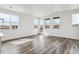 Bright living room with beautiful gray wood floors, large windows, and a door to the outdoor balcony at 6794 Merseyside Ln, Castle Pines, CO 80108