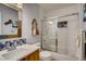 Stylish bathroom featuring modern vanity, mirror and tiled shower-bath combo with sliding glass door at 9451 Desert Willow Trl, Highlands Ranch, CO 80129