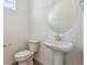 Clean half bathroom features a pedestal sink, decorative mirror, and modern toilet at 9672 Cathay St, Commerce City, CO 80022