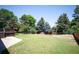 Spacious backyard with lush green grass, mature trees, wood fence and partial view of a raised deck at 6705 E Jewell Ave, Denver, CO 80224