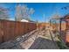 Spacious fenced backyard with a gate offering privacy, complemented by mature trees and foliage at 3613 Julian St, Denver, CO 80211