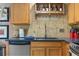 View of the kitchen sink, countertops, backsplash, wooden cabinets, and a wine rack at 11062 Gaylord St, Northglenn, CO 80233