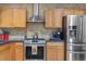Well-lit kitchen with stainless steel appliances, modern backsplash, and natural wood cabinetry at 11062 Gaylord St, Northglenn, CO 80233