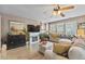 Living room showcasing hardwood floors, ceiling fan, fireplace, and an L-shaped couch near bright windows at 11062 Gaylord St, Northglenn, CO 80233