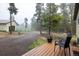 Cozy deck with chairs, a potted plant, and a view of trees, meadow, and the garage at 1194 Camp Eden Rd, Golden, CO 80403