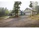 Charming home features a spacious driveway and an attached two-car garage nestled amongst mature pine trees at 1194 Camp Eden Rd, Golden, CO 80403