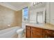 Bathroom with a toilet, sink, mirror, vanity and tub with tile surround and a window at 11845 Mobile St, Commerce City, CO 80022
