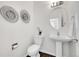 Stylish powder room with pedestal sink, round mirror, and modern wall art at 11845 Mobile St, Commerce City, CO 80022