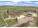 Aerial view of a ranch home with outbuildings, detached garage, and white fencing on a vast, beautiful landscape at 32501 E 137Th Way, Brighton, CO 80603