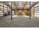 Spacious barn interior featuring wood beams, skylights, and hay covered flooring at 32501 E 137Th Way, Brighton, CO 80603