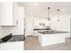 Bright kitchen showcasing white cabinets, black countertops, a central island, and modern lighting fixtures at 9264 Biscay St, Commerce City, CO 80022